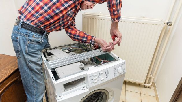 Un hombre arreglando una lavadora