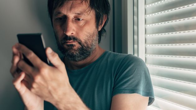 Un hombre con rostro serio consultando el móvil