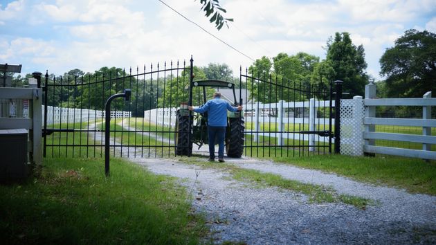 Un hombre abriendo una valla para pasar con su tractor