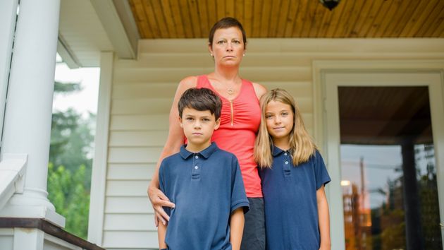 Una madre con sus hijos en la puerta de una casa 