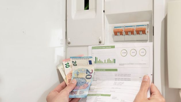 Billetes de euros y factura de luz junto un contador 