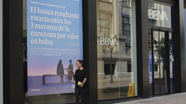 Una mujer pasando por una oficina de BBVA
