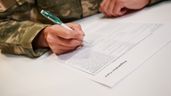 Una persona vestida de militar firmando un documento 