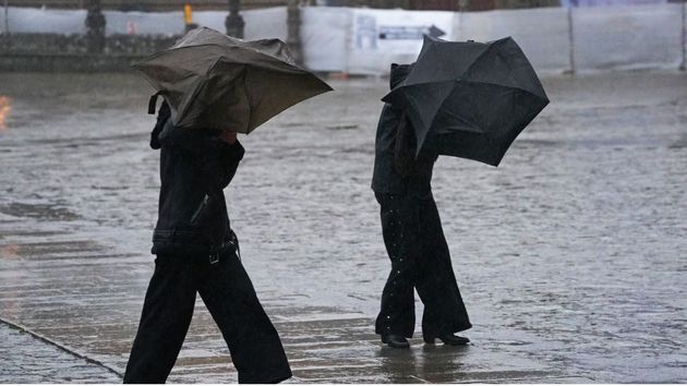 Dos personas luchando contra la lluvia.