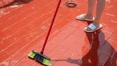 Una persona barriendo agua del suelo de una terraza mojada