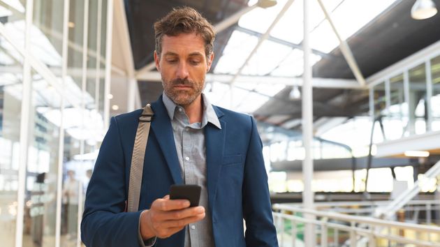 Un hombre viajando por trabajo consultando su móvil