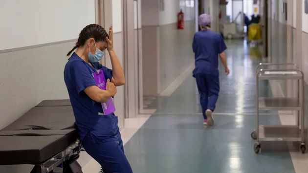 Una enfermera, cansada, en un pasillo