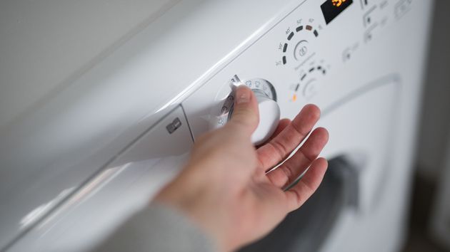 una mano encendiendo una lavadora