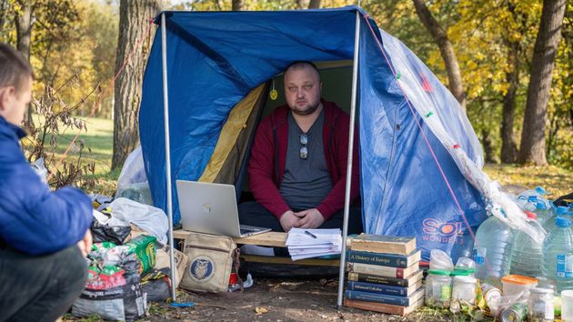 un hombre en una tienda de campaña con libros y un ordenador