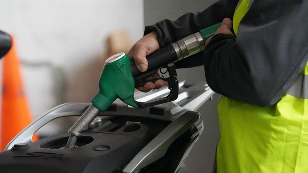 una persona echando gasolina a la moto