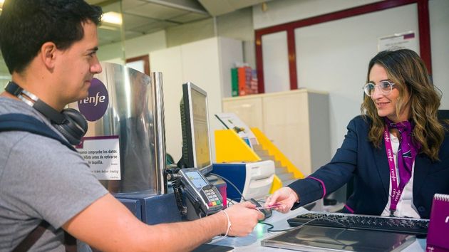 una empelada de renfe atendiendo a un viajero
