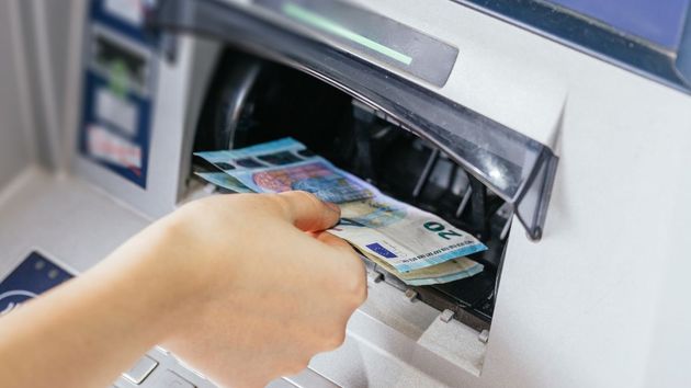 una mano cogiendo billetes de un cajero automático