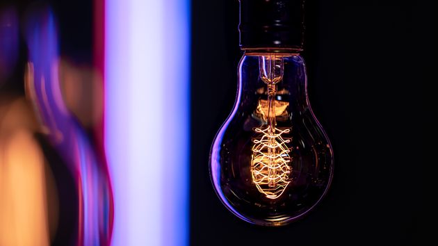 Una bombilla de luz encendida, con destellos violetas