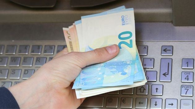 Una persona saca dinero de la prestación por desempleo de un cajero automático