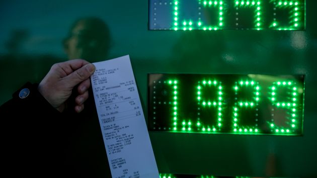 Una persona muestra un ticket de repostar gasolina en una estación de servicio