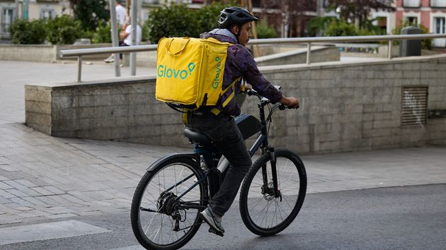 Un repartidor de Glovo en bicicleta por una calle de Madrid