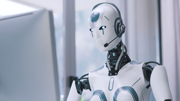 Un robot con un micrófono delante de un ordenador