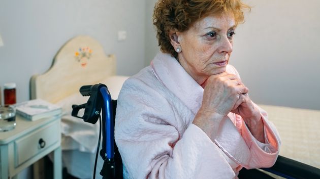 Mujer mayor en silla de ruedas mirando a la ventana