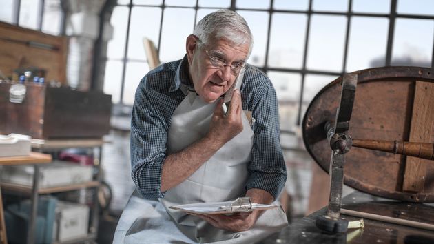 Un hombre mayor hablando por teléfono en su anticuario