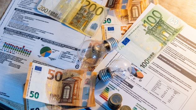 Bombillas y dinero en efectivo sobre varias facturas de luz