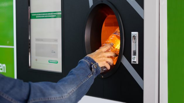 Mano entregando una botella en maquina de envases