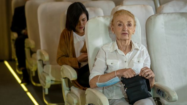 Una mujer mayor con un bolso sentada en un avión