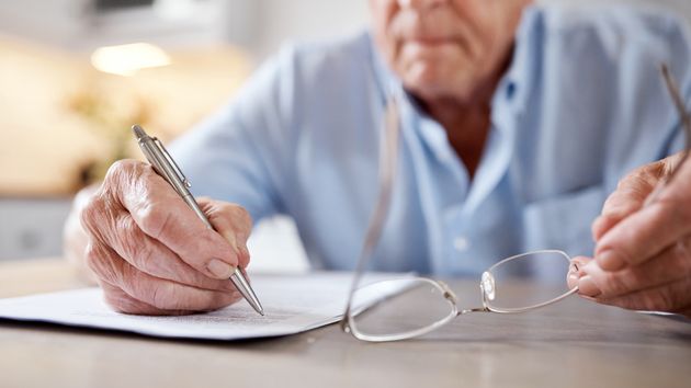 Un anciano firmando un documento 
