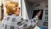jubilada sacando el dinero de su pensión de un cajero automático