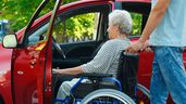 Una anciana en silla de ruedas subiendo a un coche 