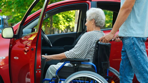 Una anciana en silla de ruedas subiendo a un coche 