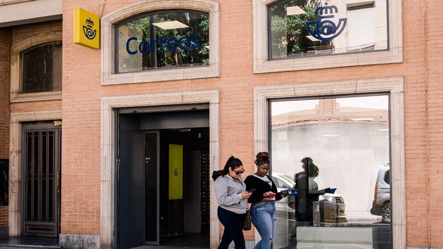 Dos personas pasando por una oficina de Correos