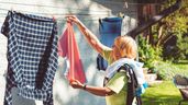 Una mujer tendiendo la ropa en el jardín