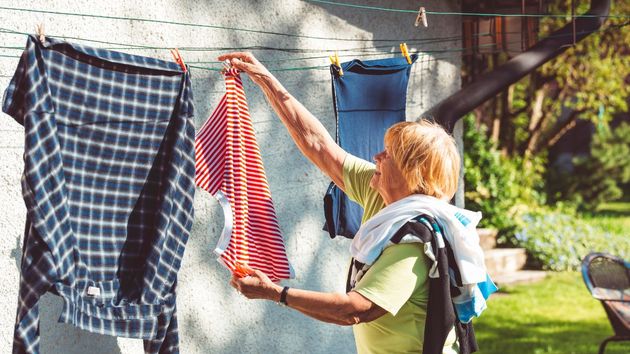 Una mujer tendiendo la ropa en el jardín