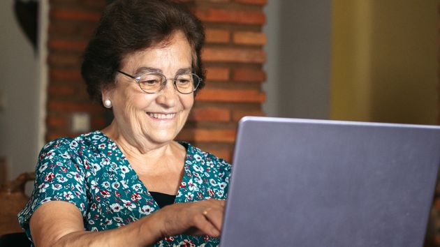 Una mujer mayor mira un portátil