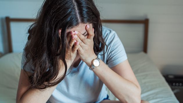 Una mujer con las manos en la cabeza, llorando