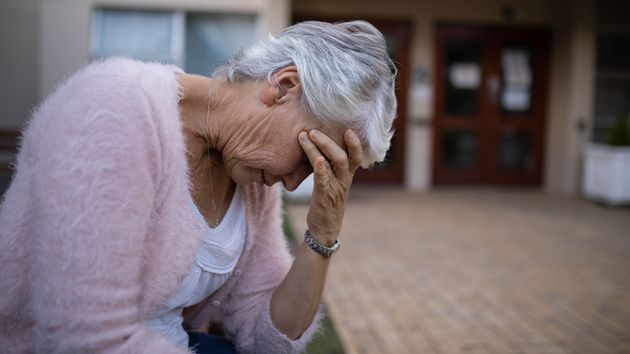 Una mujer mayor llora sentada