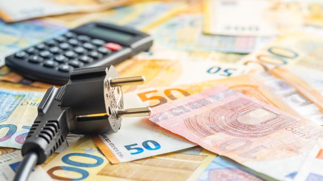 Un enchufe con una calculadora y billetes de euro