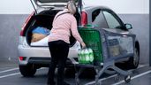 Una mujer mete la compra en el maletero de su vehículo
