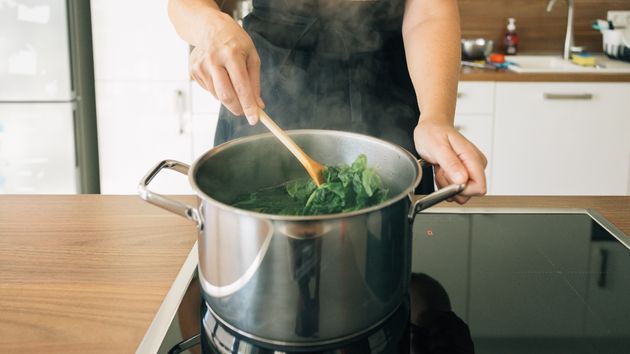 Una persona está cocinando espinacas en una olla