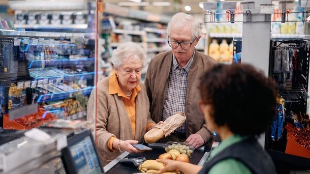 Do ancianos pagando en la caja de un supermercado
