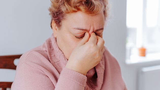 Una mujer mayor llorando con la mano en la nariz