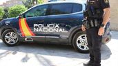 Un policía nacional junto a un coche oficial
