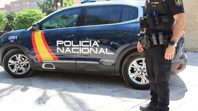 Un policía nacional junto a un coche oficial
