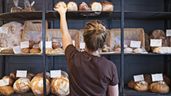 Una mujer coloca panes en su panadería
