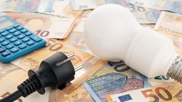 Una bombilla y un enchufe sobre billetes de euro