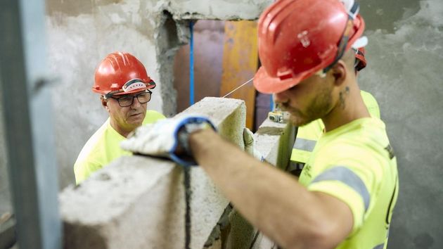 Dos albañiles trabajan levantando un tabique