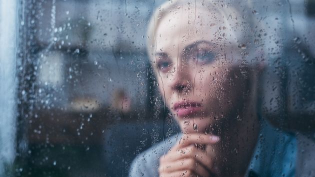 Una mujer mirando llover por la ventana