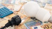 Una bombilla y un enchufe sobre billetes de euro
