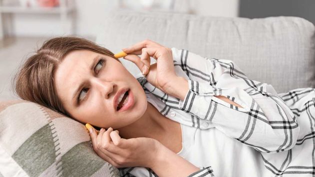 Una mujer poniéndose tapones en los oídos 