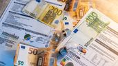 Dos bombillas sobre billetes, monedas y facturas